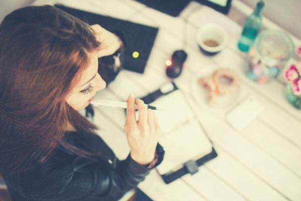 young-woman-thinking-with-pen-while-working-studying-at-her-desk