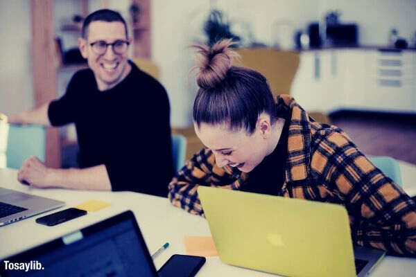 colleagues laughing man woman office laptop