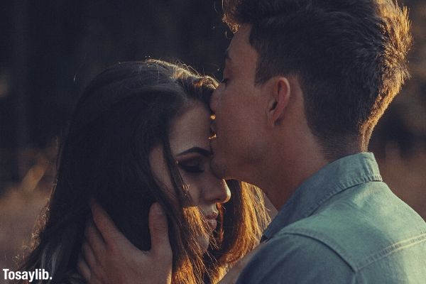 man kissing woman on the forehead