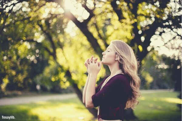 woman praying tree day time grass