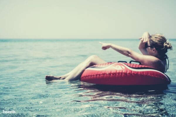 woman pointing ocean riding inflatable float sky