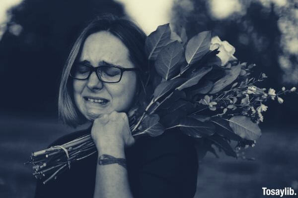 woman mourning crying while holding flowers