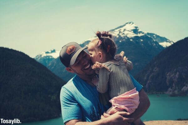 man carrying her daughter smiling mountains lake