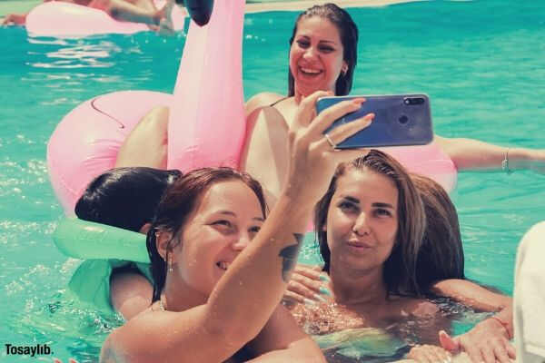 women swimming pool taking photo inflatable flamango
