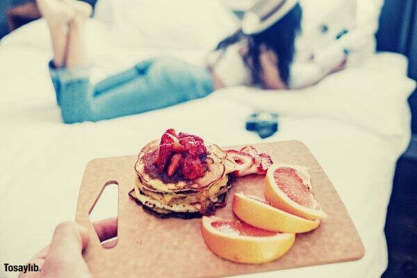 selective focus person holding tray of foods woman lying on bed