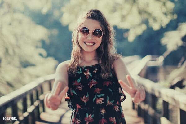 woman smiling peace sign sunglasses bridge tree