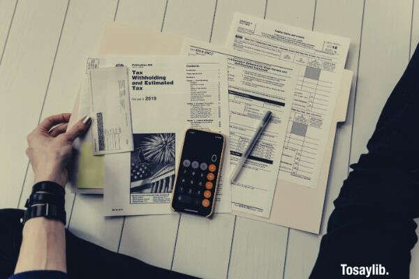 photo of person holding pen calculator clips coins