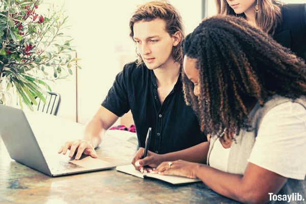 man working on laptop while woman takes notes