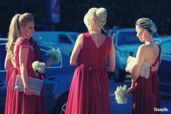 three women facing each other red gown cars