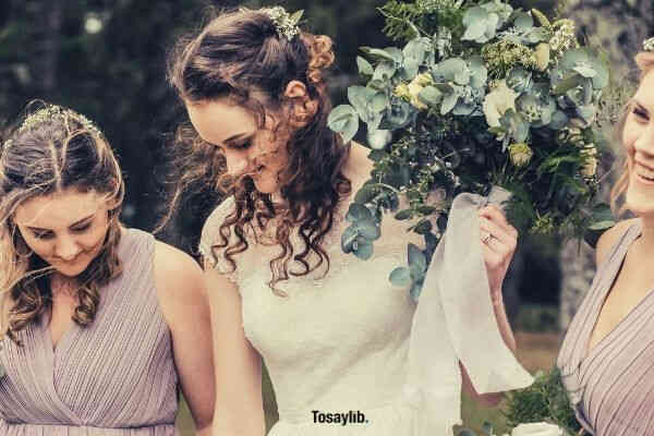 photo of women wearing white beige dress holding green white flower bouquet