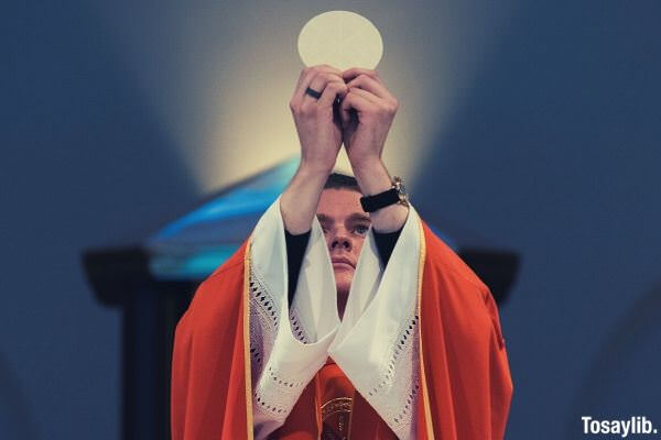 01 priest red robe offering communion in front of altar