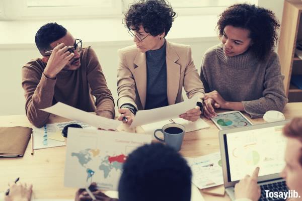 01 photo of people sitting near table holding papers