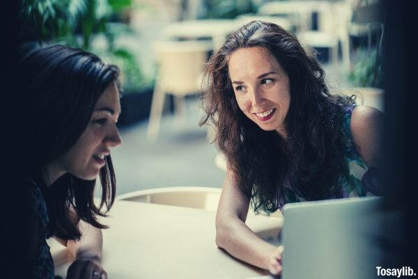 two talking women while using laptop