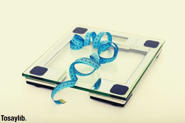 blue tape measuring on clear glass square weighing scale