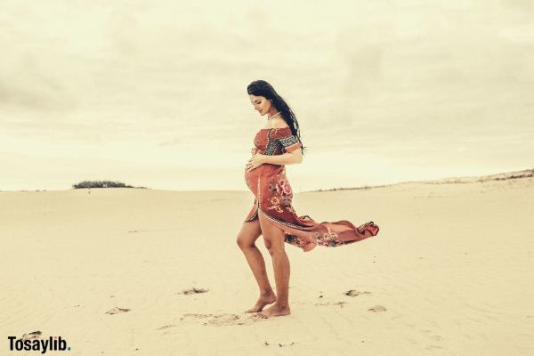 woman holding her womb sand dress brown