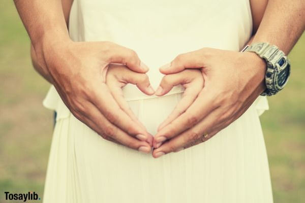 couple wearing white clothes forming heart shape hands