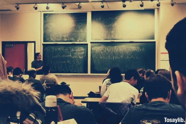 student sitting on chairs in front of chalkboard