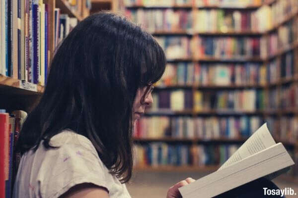 woman reading book inside the library