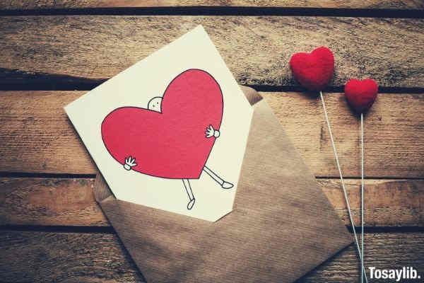 white black and red person carrying heart illustration in brown envelope