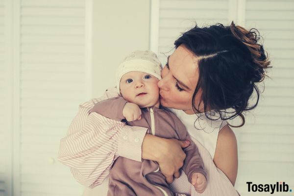 woman in pink and white kissing her baby