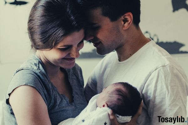 mom and dad looking at their baby while standing