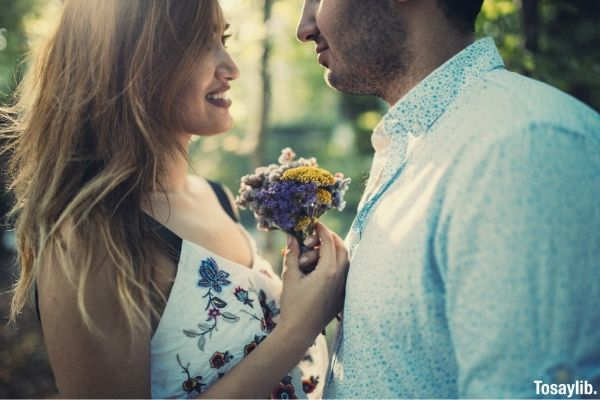 woman holding flowers in front of man