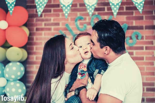 photo of a man and woman kissing their baby