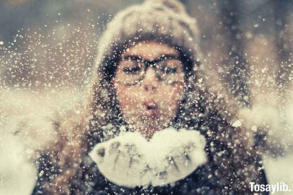 woman blowing snow outside
