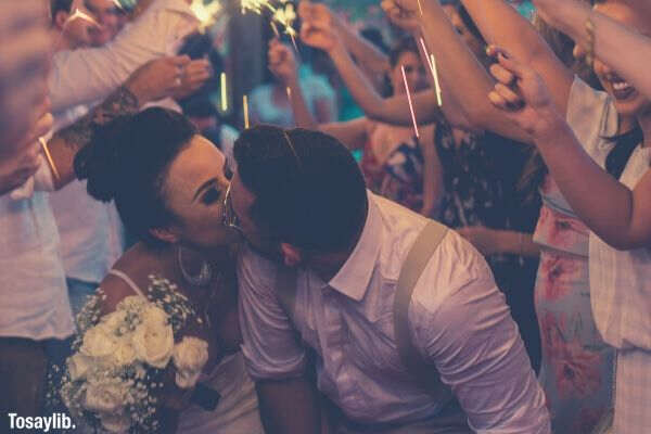 newly wed kissing surrounded by people holding stick of light