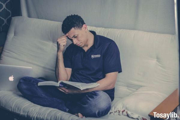 man sitting on sofa reading book