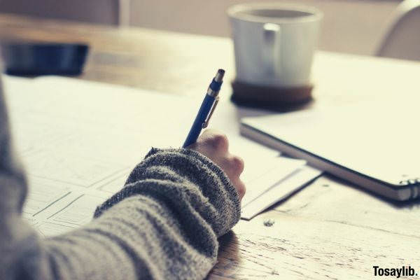 07 person writing on brown wooden table