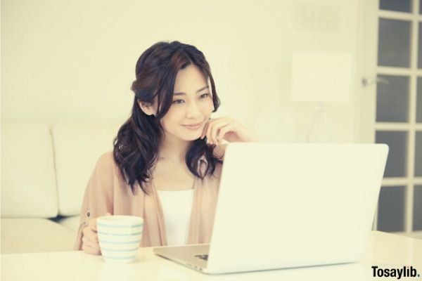 woman looking laptop drinking coffee