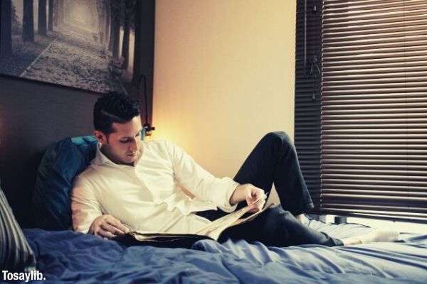 airbnb image man reading book lying on bed