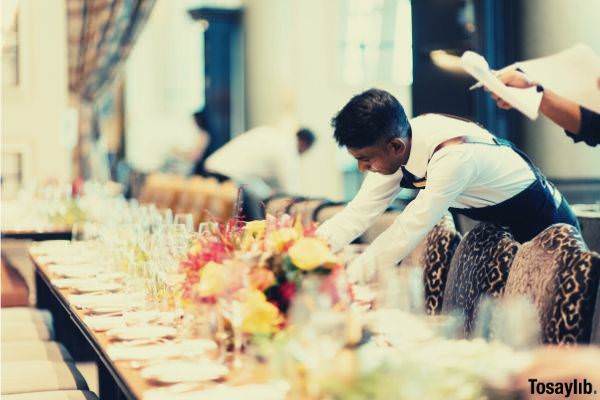 man organizing table plates glasses flowers