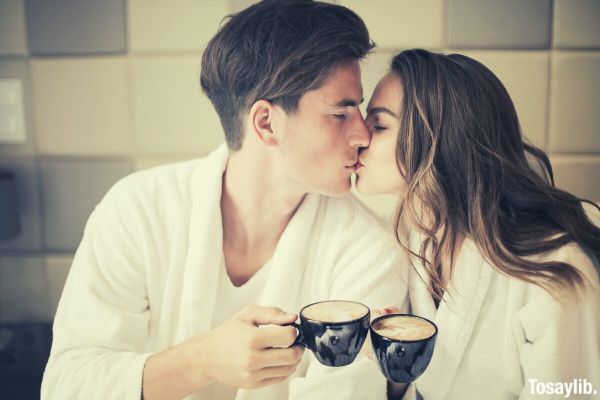 couple kissing while drinking coffee