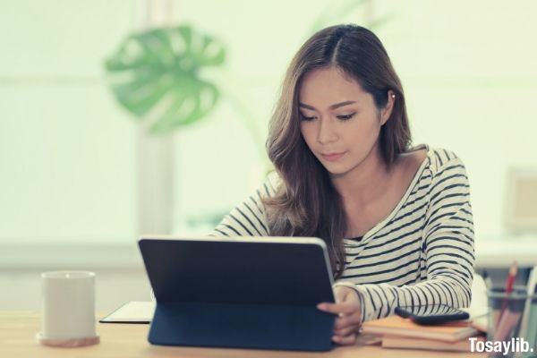 woman in black and white striped dress shirt using black tablet computer