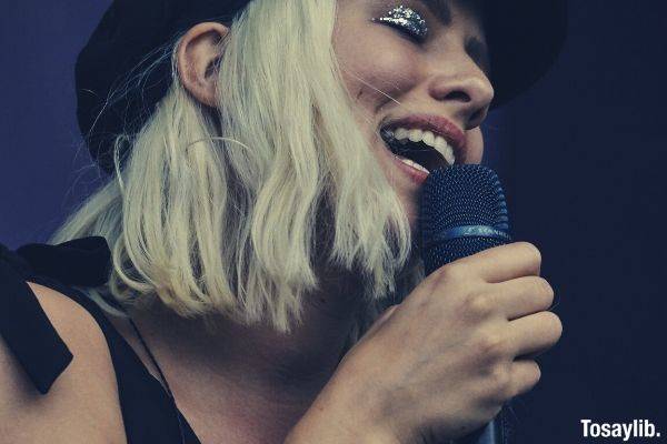 close up photography of a woman with hat holding microphone