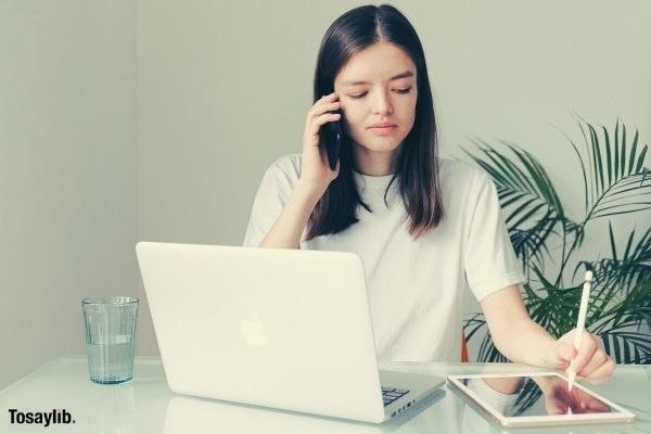 01 woman in white crew neck t shirt using silver macbook tablet calling phone