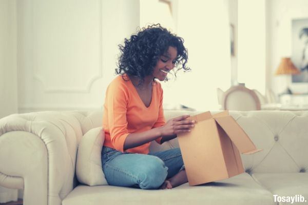 cheerful african american woman unpacking parcel