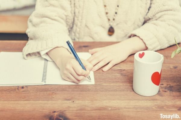 woman taking notes in notebook mug hearts