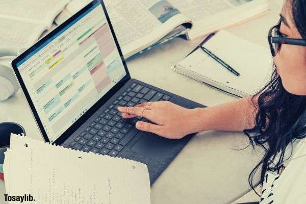 woman typing laptop holding computer books notebook table pen