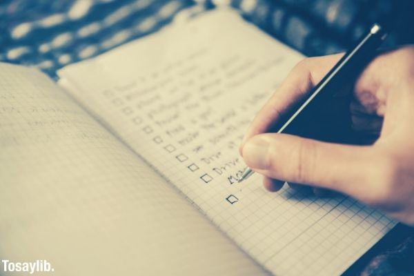 person writing bucket list on notebook with grids