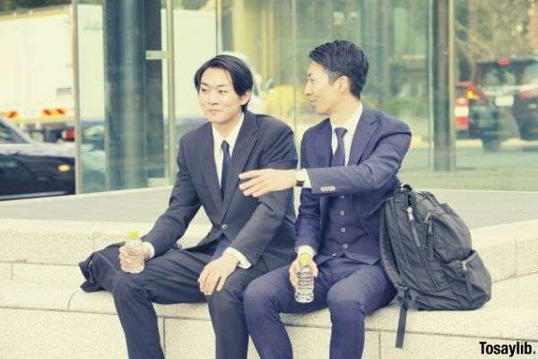 businessman two men sitting on the side walk having conversation holding water