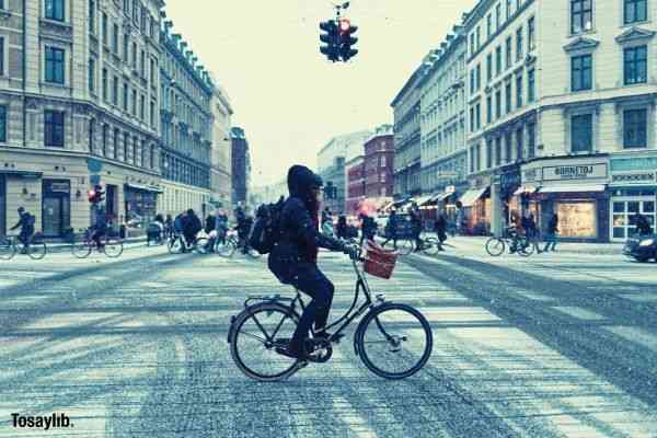 person riding bike cross road buildings stoplight