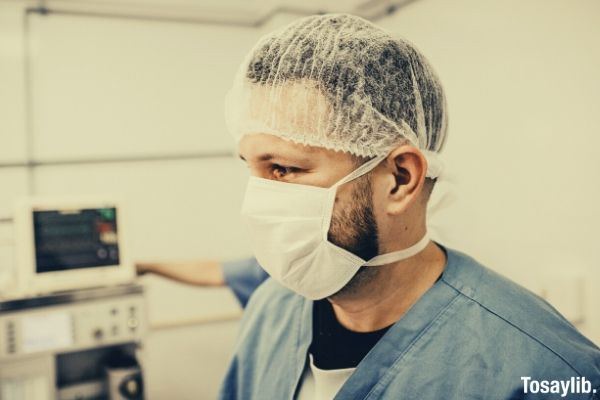 man wearing scrub suit and mask looking on something