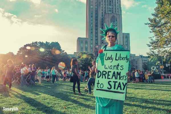 woman holding signage liberty people grass building