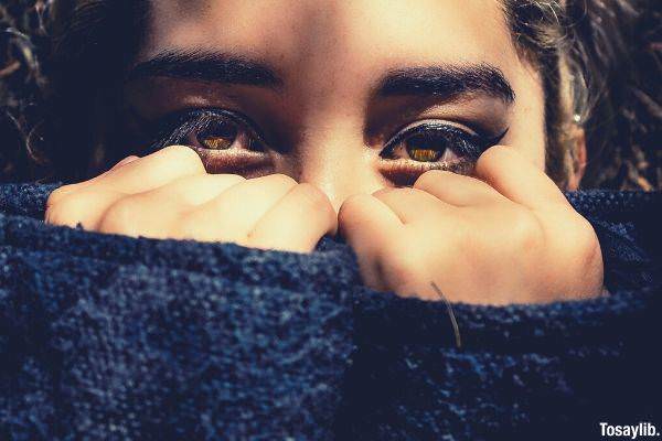 woman covering her face and leaving his eyes using her sweater