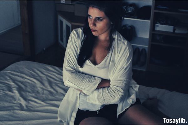 woman wearing white cardigan sitting on the bed