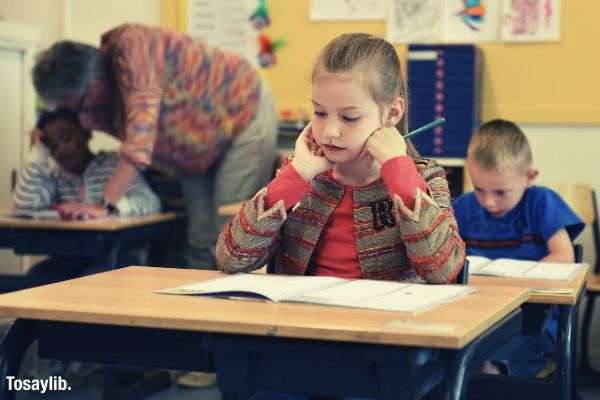 children having their exam girl holding pencil answering test paper