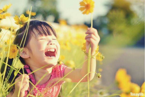 child holding flower on flower field
